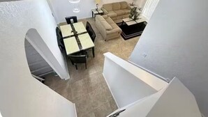 A dining area with a table and chairs, a sofa, and a small side table with a lamp. - 324 Palermo Villa 30 min to Disney and Universal (Davenport)