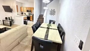 A modern kitchen with wooden cabinets, a dining area with a marble table, and a staircase leading to another level. - 324 Palermo Villa 30 min to Disney and Universal (Davenport)