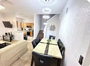 Eine moderne Küche mit Holzschränken, ein Essbereich mit einem Marmortisch und eine Treppe, die zu einer weiteren Ebene führt.