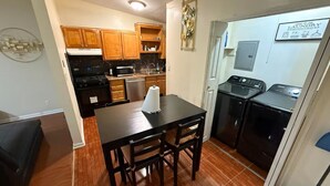 A kitchen with wooden cabinets, a dining table, and a refrigerator.