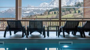 A pool area with three lounge chairs and a view of snow-capped mountains.