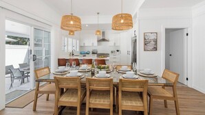 A dining area with a glass table, wicker chairs, and hanging wicker lamps.