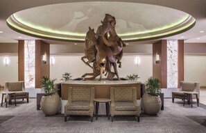 Eine Lobby mit einer zentralen Skulptur, Sitzgelegenheiten und einem modernen Deckenstil.