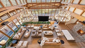 Een ruim interieur met een hoge plafond, grote ramen en een stenen openhaard.