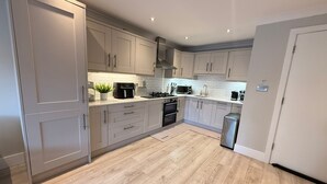 Une cuisine moderne avec des armoires blanches, une cuisinière en acier inoxydable et un plancher en bois.