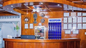 Una recepción con un cartel azul, diplomas enmarcados y un reloj en la pared.
