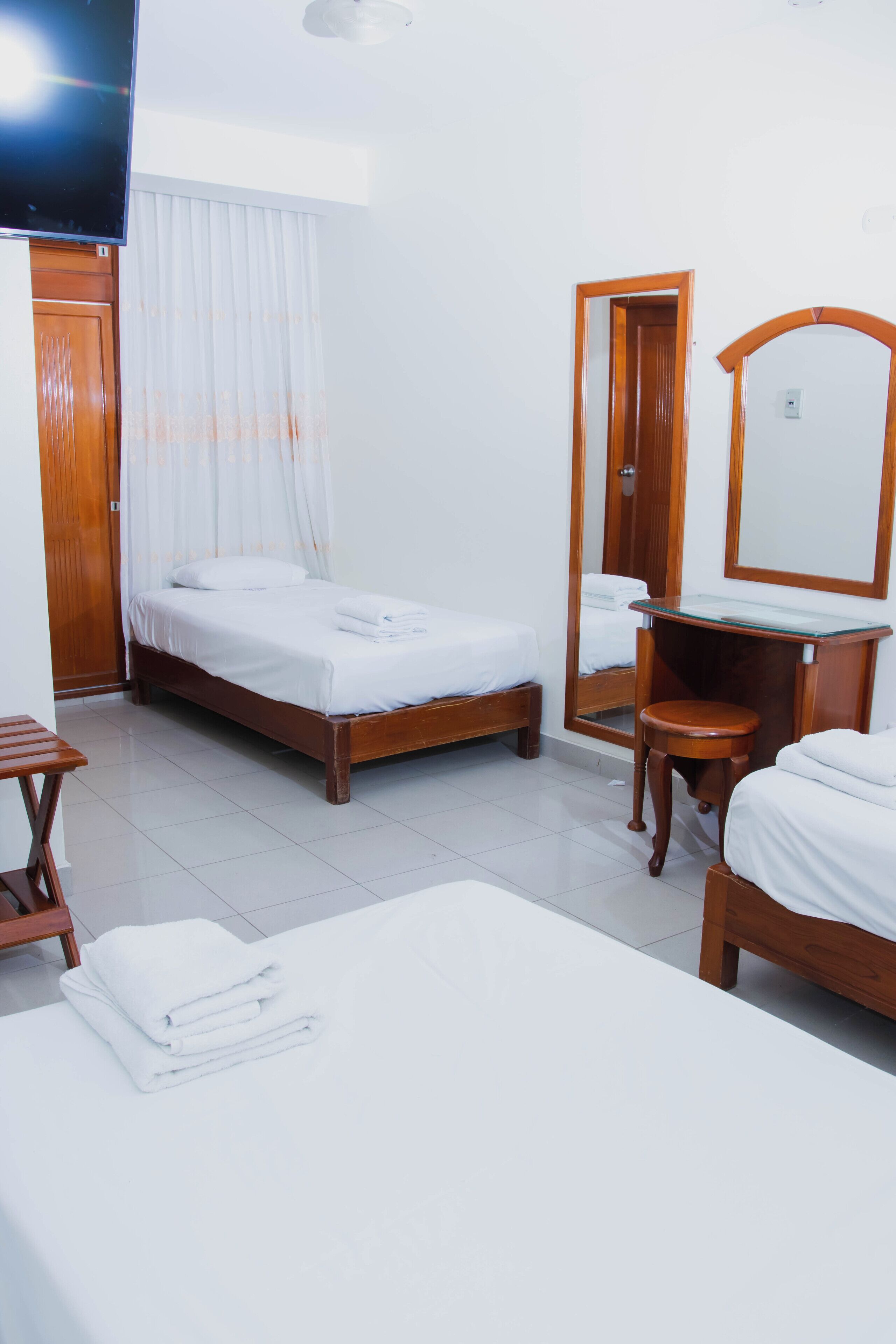 A hotel room with a bed, a bedside table, a mirror, and a television.