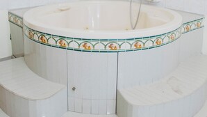 Un baño con bañera independiente, ducha y barra de apoyo.