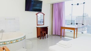 Habitación de hotel con cama, escritorio, silla, ventana grande con vistas y bañera.