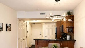 A modern kitchen with wooden cabinets, a glass dining table, and a chandelier. - "Alpine Hideaway" at Alpine Village (Canmore)