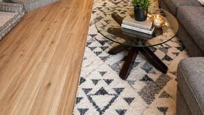 A staircase leading to a kitchen with a dining area, a living room with a sofa and a coffee table, and a patterned rug. - "Alpine Hideaway" at Alpine Village (Canmore)