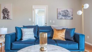 Ein Wohnzimmer mit einem blauen Sofa, einem Marmor-Couchtisch und zwei Wandlampen.