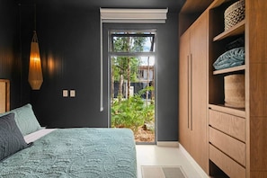 A bedroom with a bed, a window, a wardrobe, and a hanging light fixture.