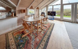 A wooden interior with a dining table, chairs, a TV, and a view of the outdoors. - Lovely home in Sydals with sauna (Sydals)