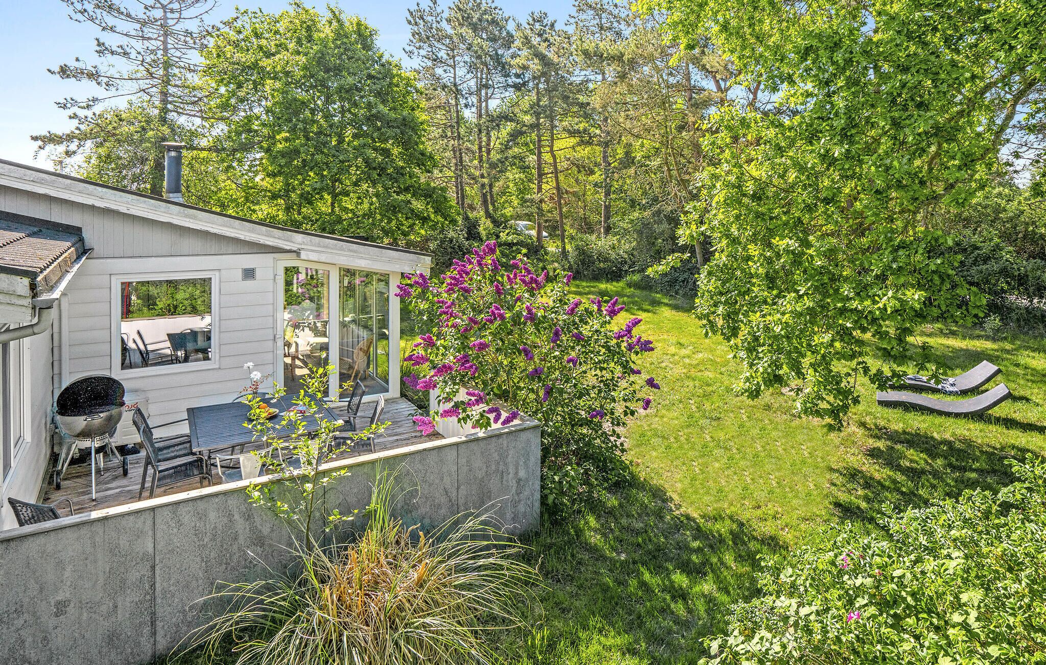 Une maison dotée d’un patio, d’un jardin et offrant une vue sur les arbres environnants.