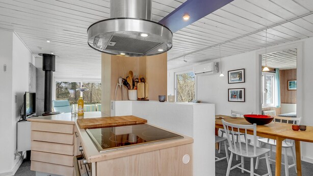 Una cucina moderna con piano cottura integrato, mobili in legno e un'ampia finestra.