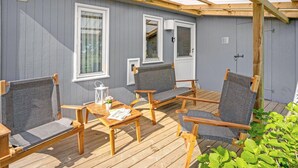 Un'area relax esterna coperta con mobili in legno, un tavolo, una porta e finestre.