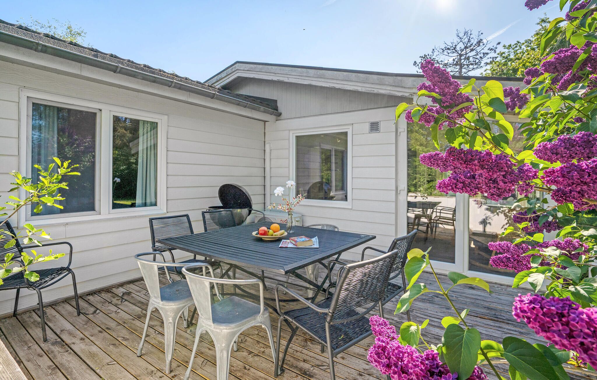 A patio with a table and chairs, a grill, and a view of the house.