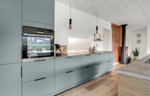 A modern kitchen with a large island, stainless steel appliances, and a wood-burning stove. - Beautiful home in Sydals with WiFi (Sydals)