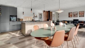 A modern kitchen with a central island, a dining area with a round table and chairs, and a living area with a sofa and artwork on the wall. - Beautiful home in Sydals with WiFi (Sydals)