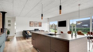 A modern kitchen with a large island, wooden cabinets, pendant lights, and a view of the outdoors. - Beautiful home in Sydals with WiFi (Sydals)