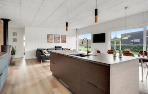 A modern kitchen with a large island, wooden cabinets, pendant lights, and a view of the outdoors. - Beautiful home in Sydals with WiFi (Sydals)