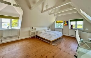 A bedroom with a bed, a small bedside table, a window, and a radiator.