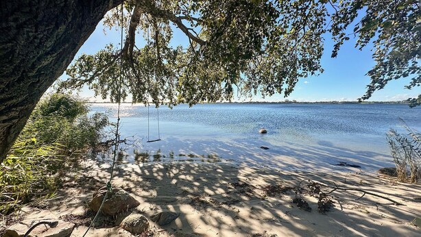 A sandy beach with a swing set, trees, and a calm body of water. - 3 bedroom gorgeous home in Sydals (Sydals)