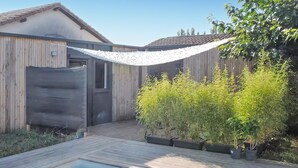 A wooden deck with a pool, a covered patio area, and potted plants. - Lovely home in Saint-Vincent-de-Paul (Saint-Vincent-de-Paul)