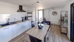 A modern kitchen with white cabinetry, a wooden countertop, and a central island with seating. - Lovely home in Saint-Vincent-de-Paul (Saint-Vincent-de-Paul)