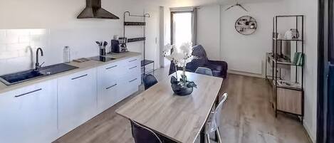 Une cuisine moderne avec des meubles blancs, un plan de travail en bois et un îlot central doté de sièges.