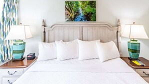 A hotel room with a bed, two bedside tables, a nightstand, a lamp, a painting, and a curtain. - 2-bedroom condo in fantastic Gatlinburg with AC (Gatlinburg)