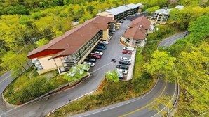 An aerial view of a hotel with a parking lot, a curved road, and surrounding greenery. - 2-bedroom condo in fantastic Gatlinburg with AC (Gatlinburg)