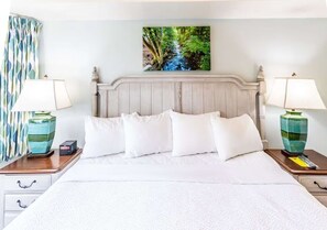 A hotel room with a bed, two bedside tables, a nightstand, a lamp, a painting, and a curtain. - 2-bedroom condo in adorable Gatlinburg with AC and fitness room (Gatlinburg)