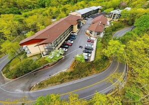 An aerial view of a hotel with a parking lot, a curved road, and surrounding greenery. - Cozy 3-bedroom condo with AC in soothing Gatlinburg (Gatlinburg)