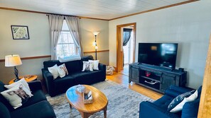 A living room with a sofa, a coffee table, a TV, and a lamp. - Lake & Trail Landing- ATV & Snowmobile Access (Greenville)