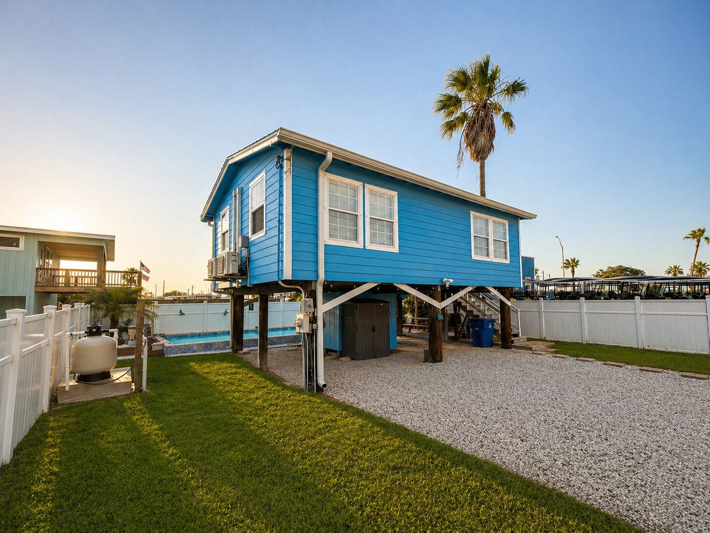 A blue house with a balcony, a palm tree, and a pool in the background.