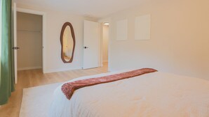 Ein Schlafzimmer mit einem Bett, einem Spiegel und einer Tür zu einem anderen Raum.
