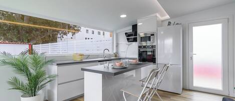 Una cocina moderna con una isla central, horno empotrado y refrigerador.