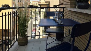 A balcony with a table and chairs, a potted plant, and a view of the street. - Townhouse 41 - Trieste - by Be Your Home (Civitavecchia)
