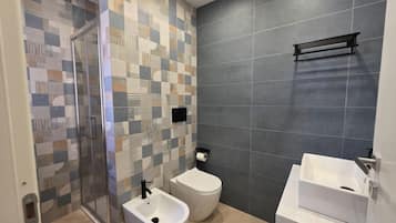 Un bagno con doccia, WC e lavandino.