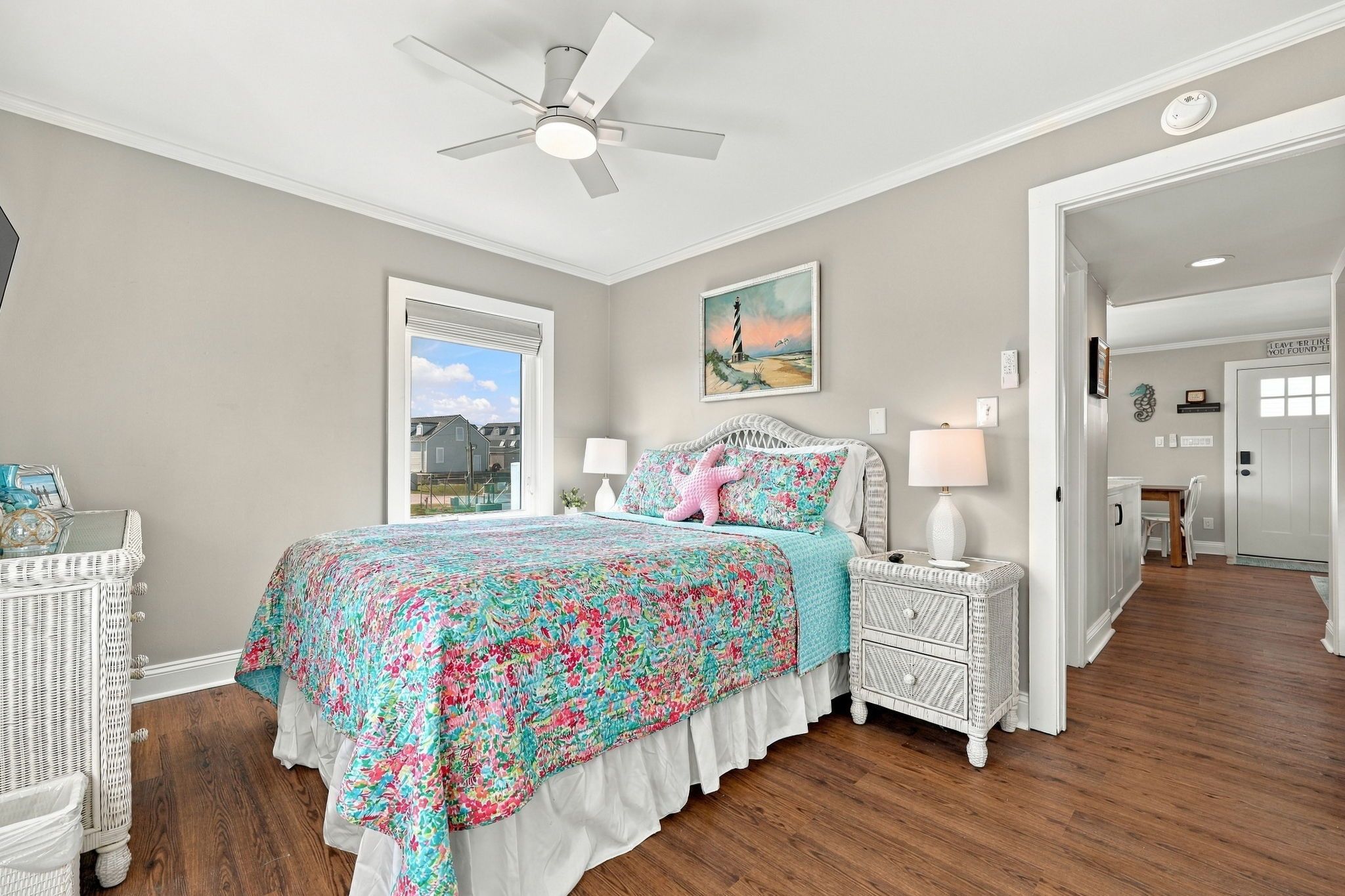 A bedroom with a bed, a nightstand, a lamp, a ceiling fan, and a window.