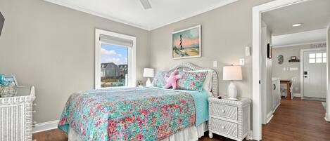 A bedroom with a bed, a nightstand, a lamp, a ceiling fan, and a window.