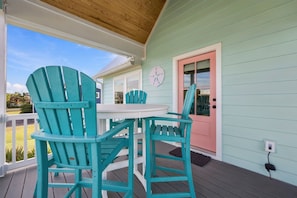 A covered porch with a table and chairs, a door with a pink frame, and a power outlet on the wall. - Coming Soon: Check out this gem at The Point.  4BR, 3BA, 3-minute walk to beach. (Emerald Isle)