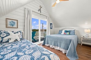 A bedroom with a large bed, a smaller bed, and a balcony with a view. - Coming Soon: Check out this gem at The Point.  4BR, 3BA, 3-minute walk to beach. (Emerald Isle)