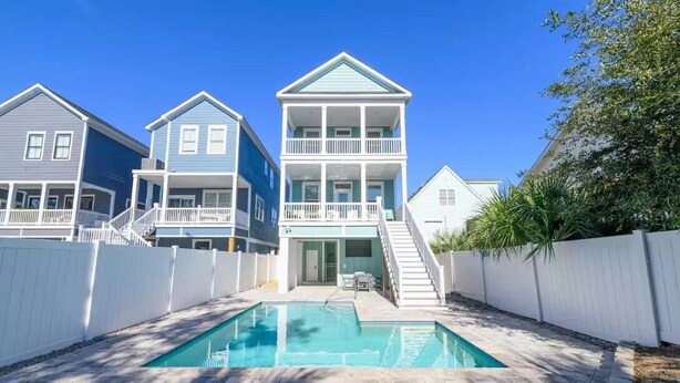Un quartier résidentiel doté d’une piscine, de clôtures blanches et de maisons avec des balcons.