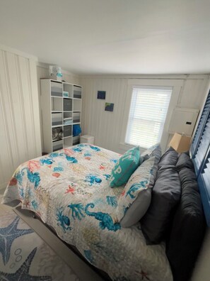 A bedroom with a bed, a wardrobe, a window, and a blue wall unit.