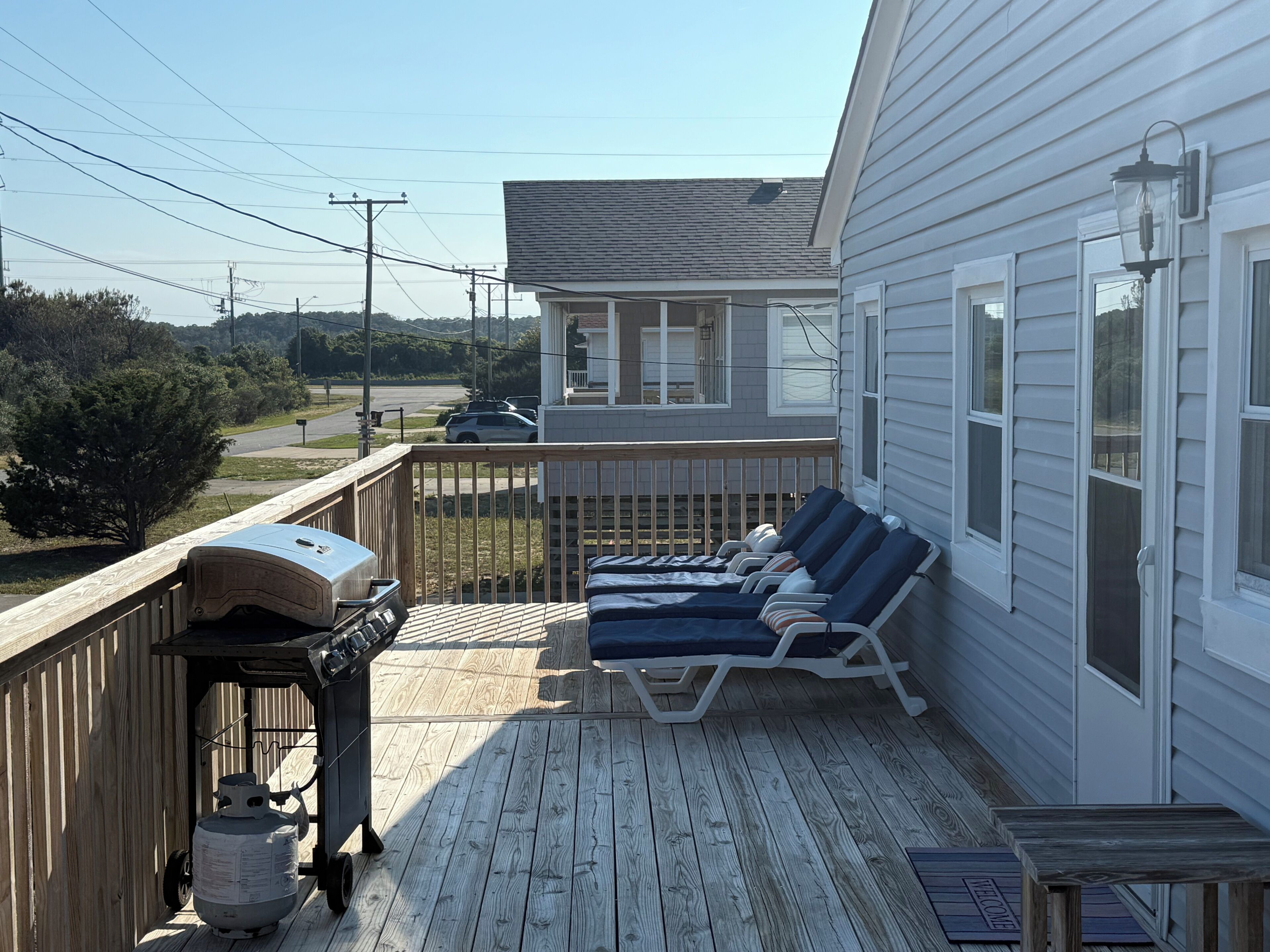 A deck with lounge chairs, a grill, and a propane tank.