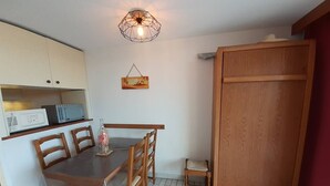 Una cucina compatta con tavolo, sedie, forno a microonde e lampadario.