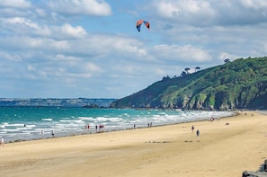 Ein Strand mit Spaziergängern und einem fliegenden Drachen.